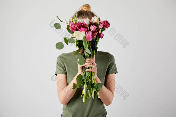 女孩拿着花束与郁<strong>金</strong>香, 桉树和玫瑰在前面的脸隔离在灰色与复制空间