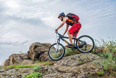 骑自行车的人顺着山上的石头往下走, 这是一种积极的生活方式。极端骑自行车对蓝天, 自由空间, 为您的文本.