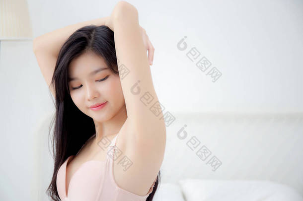 <strong>漂亮的</strong>年轻亚洲女人穿着内衣裤，在腋窝上涂上乳膏和乳液，<strong>漂亮的</strong>女孩则是苗条快乐地触摸皮肤腋窝，为身体护理、治疗、化妆品和清洁脱毛.