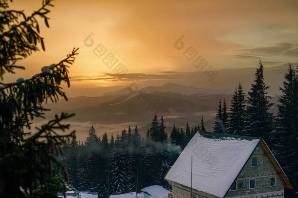 美丽的日落在雪冬山与木房子