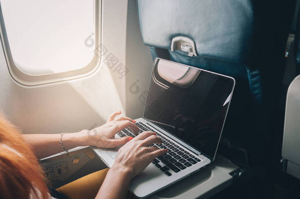 女人在飞机上使用笔记本电脑