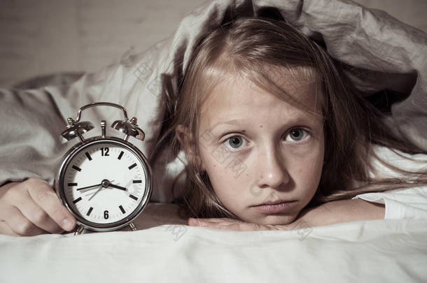 可爱的不眠之夜的小女孩在床上醒着在半夜看