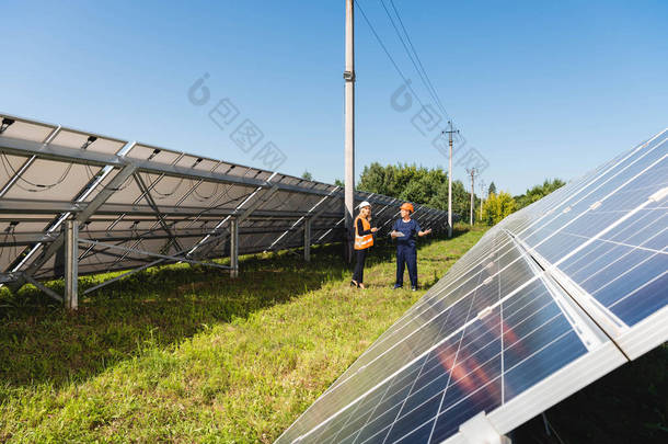 工程师和女商人在太阳能电池附近交谈和行走 