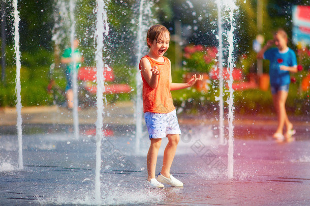 激动的男孩之间水射流，在喷泉的乐趣。在这个城市的夏天