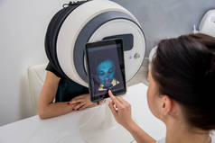 面部皮肤分析系统。 美容师分析女人的脸 现代技术.