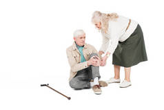 退休男子举行膝盖, 而有关节炎疼痛附近照顾妻子隔离在白色