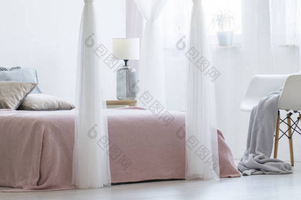 一张特大床的真实照片在平静, 平衡卧室内部的椅子上, 毯子