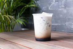 冰榴莲人参。由榴莲和潘达努斯果冻配以椰奶和棕榈糖制成的东南亚风味。用透明的塑料杯放在灰色背景的木制桌子上.