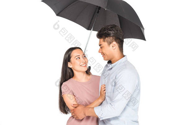 幸福的亚洲夫妇拥抱和看着对方，而站在伞下孤立的白色