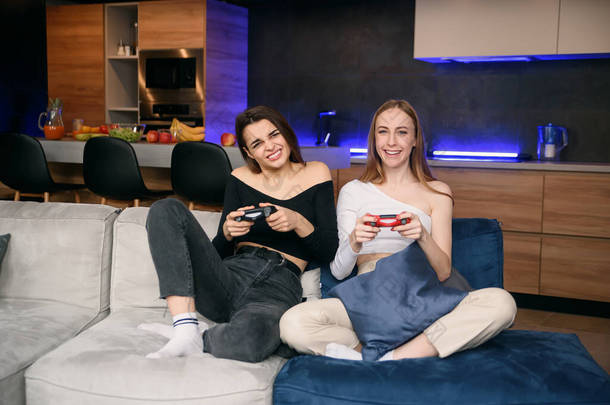 两个女朋友在家里玩兴奋的电子游戏，同时有休息时间。与朋友共渡<strong>佳节</strong>.