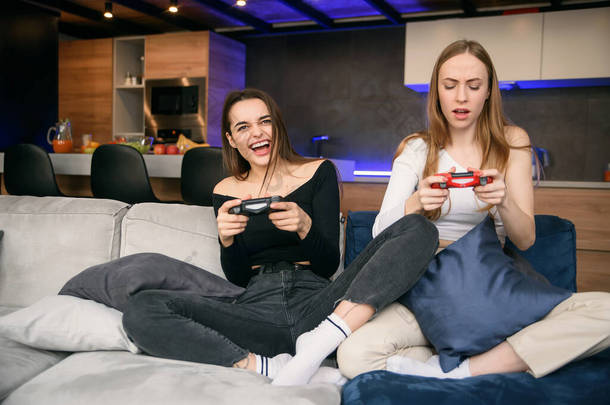 两个女朋友热衷在家里玩电脑游戏，同时还被隔离了。世界大流行病家庭隔离。享受闲暇的时光.