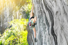 在阳光明媚的夏日，女登山者在没有保险的情况下攀登悬崖