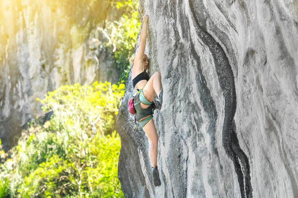 在阳光明媚的夏日，女登山者在没有保险的情况下攀登悬崖