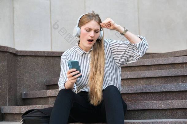 年轻美丽的女人带着耳机听着音乐，欣赏着音乐