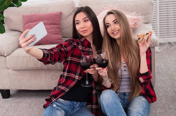 <strong>终生</strong>的友谊!美妙的年轻最好的朋友做不同的图片, 而喝红酒他们坐在地板上, 靠在米色的沙发上.
