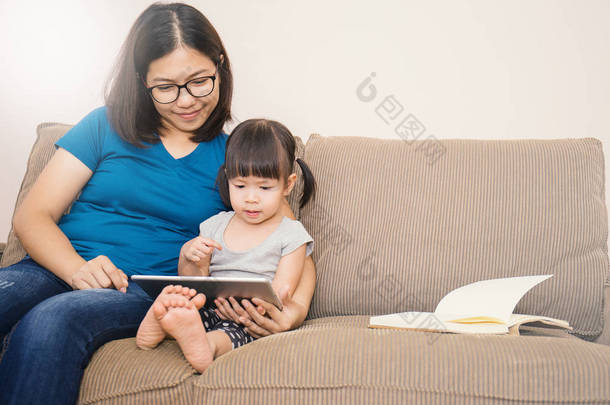 妈妈和女儿在沙发上看平板电脑