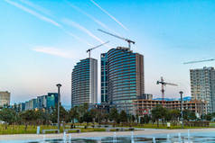 在蓝天和山的背景下, 城市建筑起重机建设高层住宅综合体的施工现场 