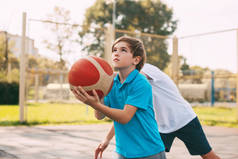 两个少年在操场上打篮球.运动员在比赛中为争取球而奋斗.健康的生活方式、运动、动机