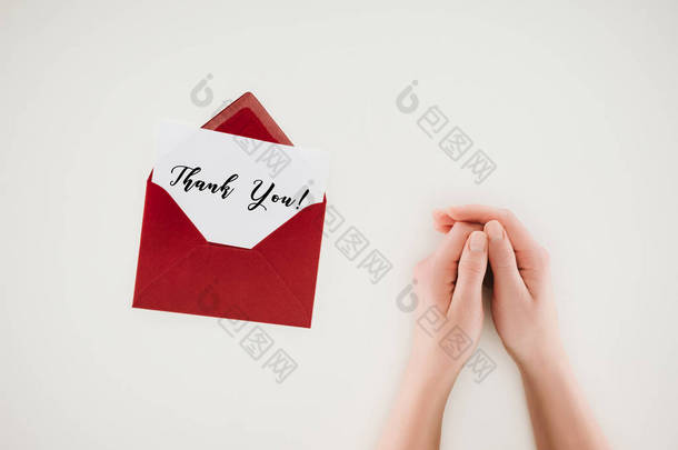 裁剪拍摄的女人手牵着手附近打开红色信封与感谢你在纸上孤立的文字在白色