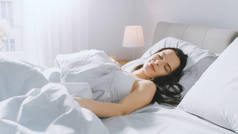 有吸引力的布鲁内特科兹利睡在她的床上,而清晨的阳光照亮她。温暖,舒适和甜蜜的美丽睡彩图片