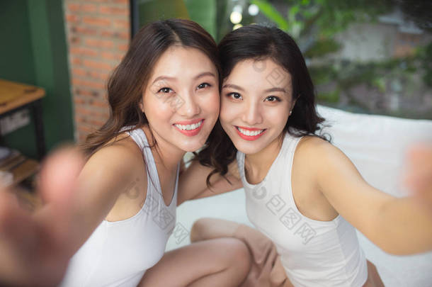 两个亚洲女人在床上的卧室里玩得很开心
