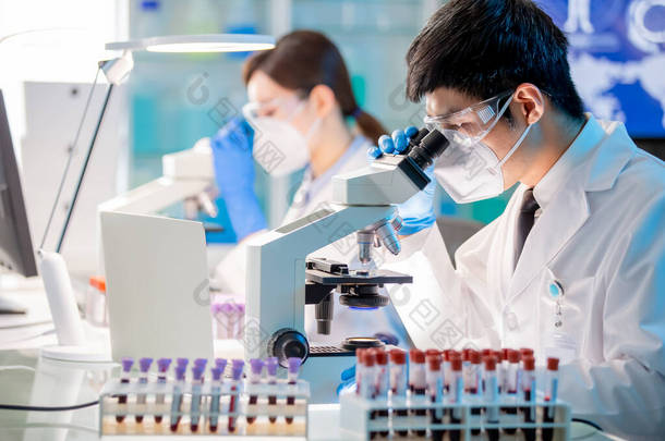 <strong>亚洲</strong>微生物学家生物技术研究人员或医务工作者在实验室内的显微镜观察