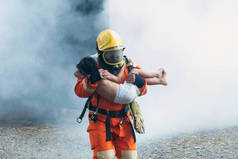 消防队员在帮助那个女孩。离开燃烧的烟雾弥漫的大楼. 
