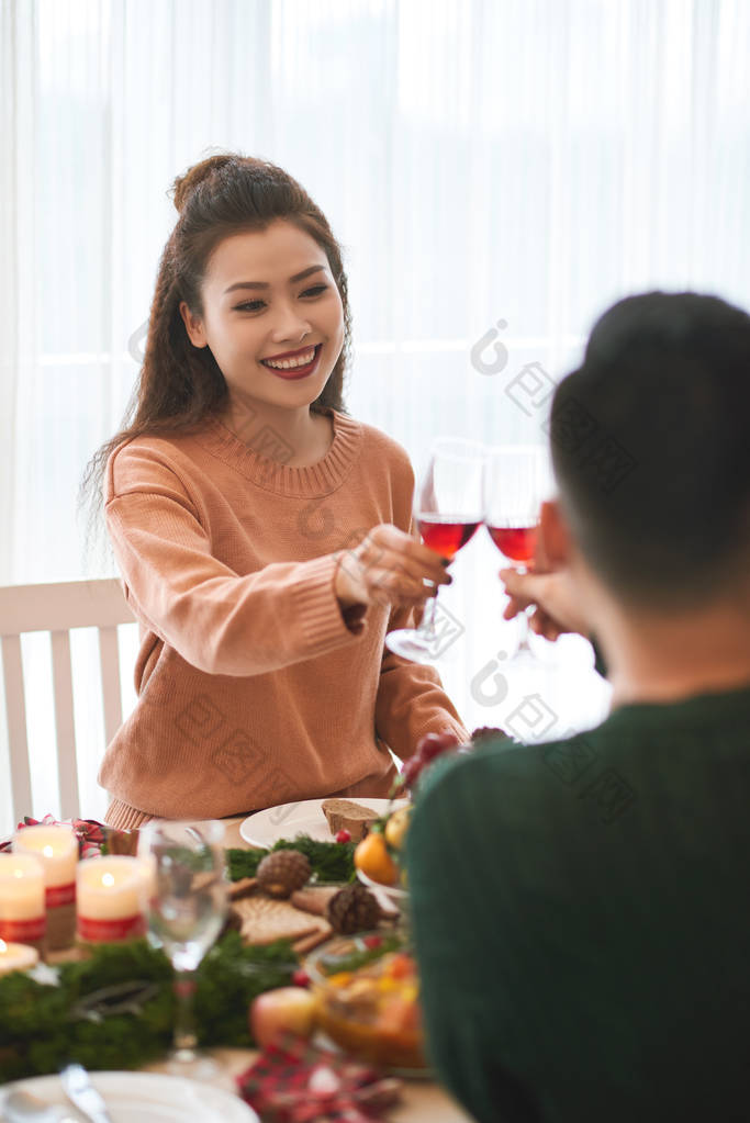 美丽的年轻越南女人和她的男朋友在圣诞餐桌上喝酒