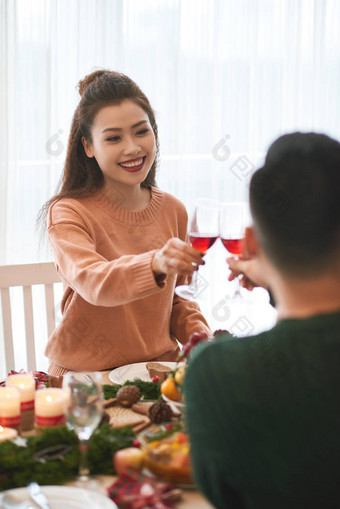 美丽的年轻越南女人和她的男朋友在圣诞餐桌上喝酒图片