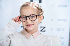 可爱的微笑的孩子看相机在眼镜在眼科咨询室