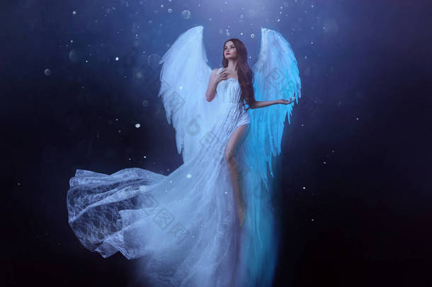 幻想中的女天使带着白色的大鸟翅膀在空中翱翔。飘浮中的鬼女孩飞了。漆黑的夜晚背景，神奇的光芒。身着白衣的女神，挥动着的面料.