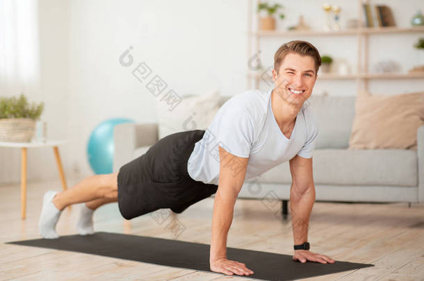 在家里健身。早上在客厅里，快乐的肌肉男在地板上铺木板