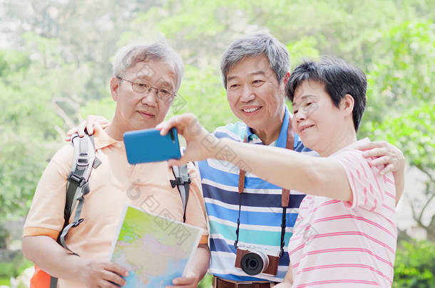 老旅行者在公园愉快地采取自拍