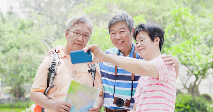 老旅行者在公园愉快地采取自拍