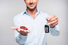 微笑的成人男子抱着汽车报警遥控和玩具红色汽车查出白色的短款镜头