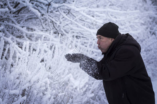 一个人在雪景中吹在他手中的雪上。