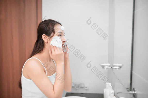 女人很高兴洁净皮肤与泡沫在浴室.