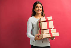 美丽的年轻拉丁妇女拿着圣诞礼物在红色背景的肖像