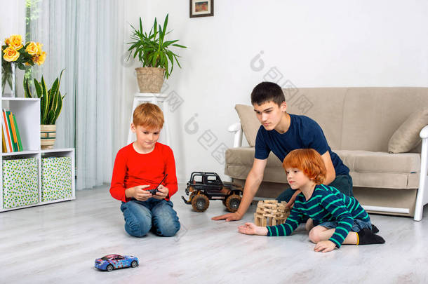 男孩们坐在房间里的地板上玩机器 