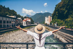 在欧洲城市的一条山上的河堤上戴帽子的快乐女孩.