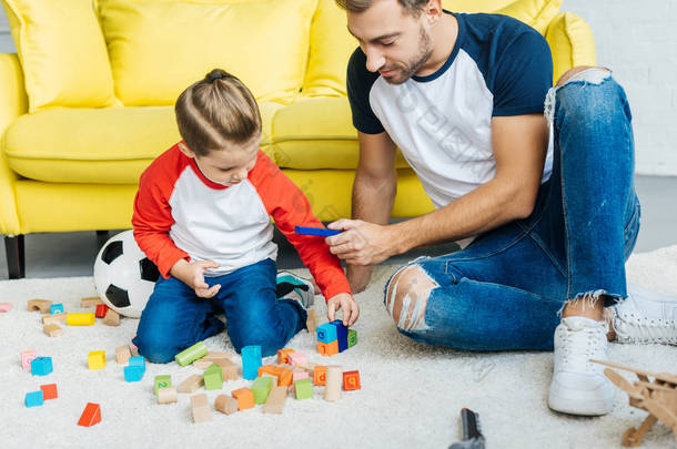 父亲和可爱的小儿子在家里玩木积木
