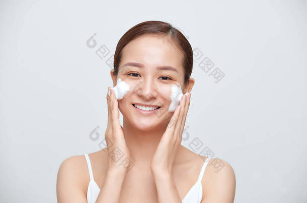 在白色背景下使用泡沫清洁剂的年轻亚洲妇女的画像.