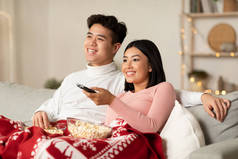亚洲配偶享受平安夜在客厅看电视的乐趣