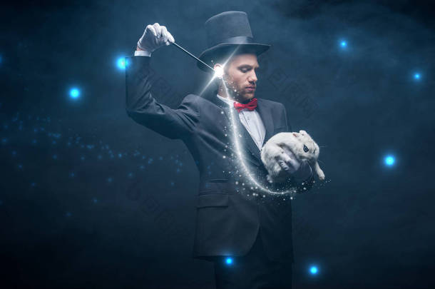 穿着西服、头戴帽子的情绪魔术师，带着魔杖和白兔<strong>表演</strong>魔术，黑漆漆的房间里挂满了烟雾和闪光的插图