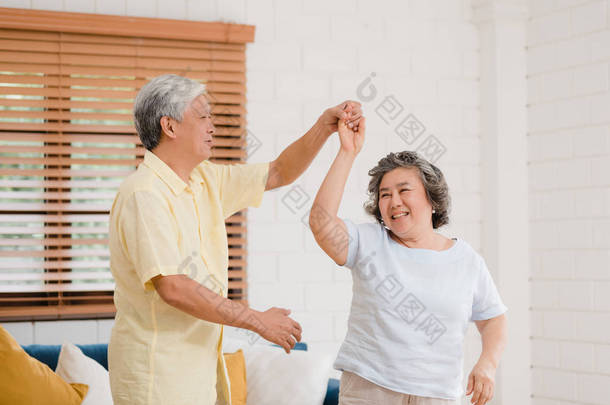 亚洲的一对老年夫妇在客厅里一边跳舞一边听音乐，甜蜜的夫妇在家里放松的时候一边享受爱情的时刻。生活方式老年人<strong>家庭</strong>在家里放松一下.