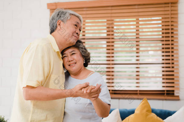 亚洲的一对老年夫妇在客厅里一边跳舞一边听音乐，甜蜜的夫妇在家里放松的时候一边享受<strong>爱</strong>情的时刻。<strong>生活</strong>方式老年人家庭在家里放松一下.