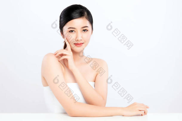 美丽的年轻亚洲女人用新鲜健康的皮肤触摸着她洁白的脸庞，被白色的背景、美容美发和面部护理理念隔离,