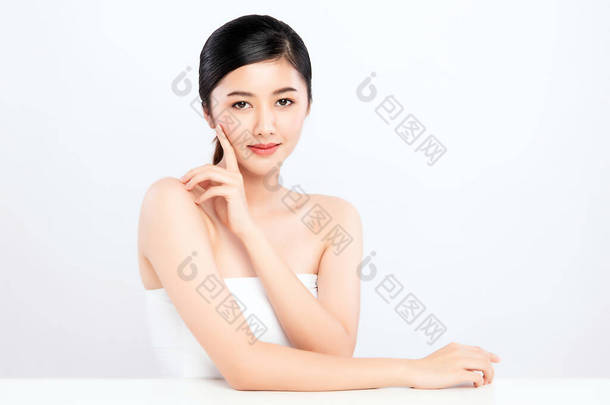 美丽<strong>的</strong>年轻亚洲女人用新鲜健康<strong>的</strong>皮肤触摸着她洁白<strong>的</strong>脸庞，被白色<strong>的背景</strong>、美容美发和面部护理理念隔离,