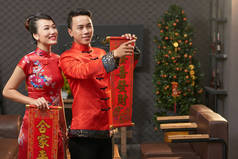 穿中国传统服饰的男子和女人用春联捧着卷轴