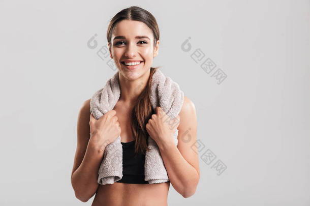年轻健身妇女的肖像摆在装毛巾的运动服 